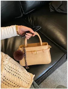 Detail of khaki bucket bag with textured pattern, plush charm and braided cord accessory