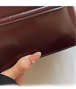 Close-up of premium dark brown leather texture and neat stitching on a vintage shoulder bag
