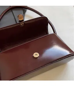 Macro shot of metallic magnetic buckle on burgundy glossy leather shoulder bag