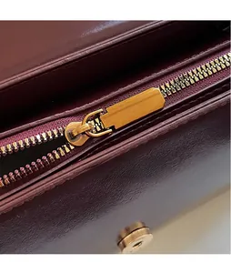 Detail of burgundy leather shoulder bag showing gold zipper and internal magnetic buckle