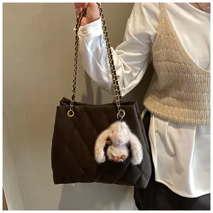 Detail van de donkerbruine gewatteerde shopper met ketting en pluche konijntje