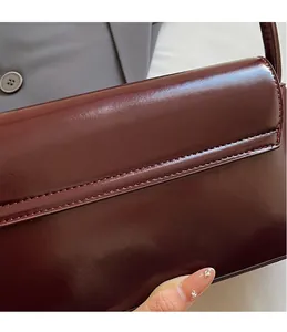 Close-up of precision stitching on a burgundy glossy leather shoulder bag detail