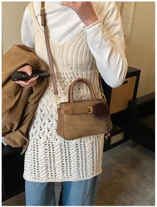 Brown bucket bag with faux fur pompom shown in a cozy mirror selfie lifestyle setting