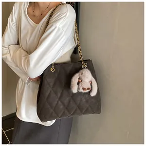 Detail van gewatteerde bruine crossbody tas met gouden ketting en pluche konijntje