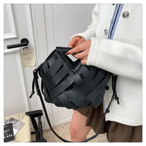 Dettaglio borsa a tracolla intrecciata nera con manico triangolare su modella in maglia