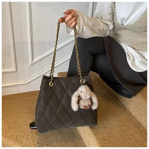 Detail van gewatteerde donkerbruine shopper met metalen kettingen en pluche konijnhanger