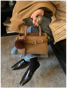 Detail of a brown vintage bucket bag with a plush charm and stylish woven strap detail