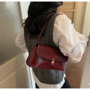 Close-up of deep wine red leather handbag featuring a vintage gold metal buckle and flap