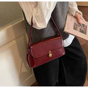 Detail of vintage burgundy shoulder bag with glossy finish and antique gold metal clasp