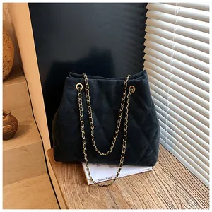 Detailopname van zwarte gewatteerde tote bag met gouden kettingband en vintage uitstraling