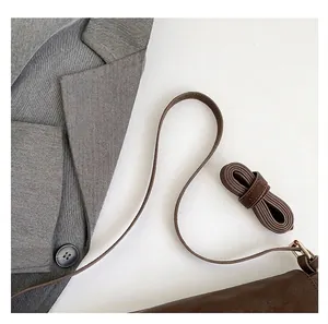 Close-up of comfortable dark brown leather shoulder strap with golden metal buckle details
