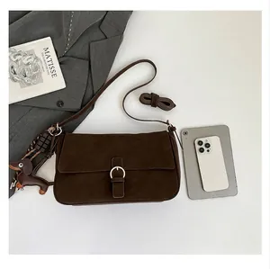 Macro view of dark brown textured leather shoulder bag showing its capacity and charms