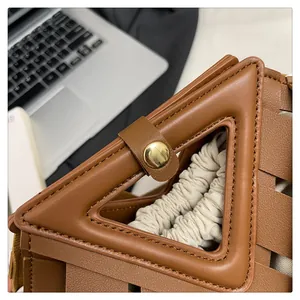 Dettaglio borsa in pelle intrecciata marrone con manico a triangolo e chiusura dorata