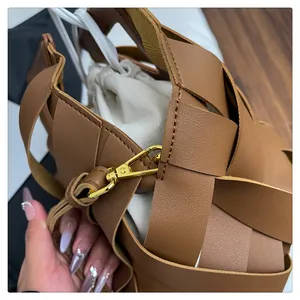 Dettaglio macro della borsa in pelle intrecciata marrone con sacchetto in tela e gancio d'oro