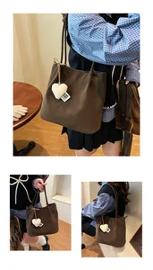 Detail of dark brown suede tote bag with plush heart charm and long shoulder strap