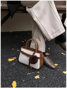 Close-up of vintage bucket bag with brown leather and white weave featuring a fuzzy charm