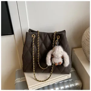 Detail van bruine gewatteerde shopper met gouden ketting en schattige pluche konijnhanger