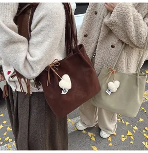 Close-up of minimalist suede tote bag with plush heart charm in an autumn street setting