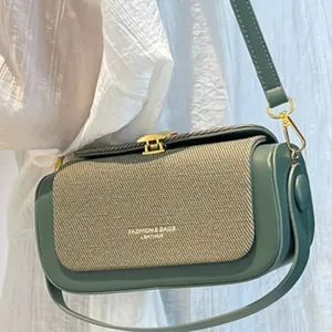 Sac bandoulière chic en cuir vert sauge et beige tissé porté par un mannequin sobre