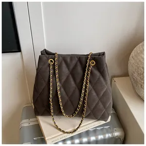 Detail van het ruitpatroon en gouden ketting op de grijze suède handtas voor dames