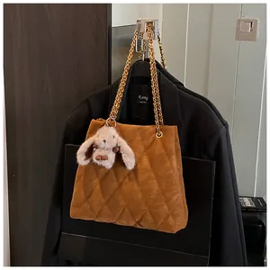 Detail van de bruine gewatteerde tas met gouden ketting en pluche konijnenhanger