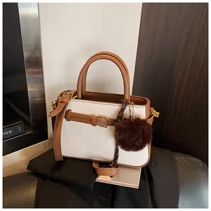 Close-up of retro bucket bag featuring woven texture, brown leather trim, and fur pom-pom
