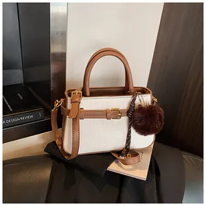Detail of woven bucket bag with brown leather trim and M-letter charm accessory