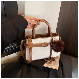 Detail of vintage bucket bag featuring textured fabric, brown leather trim and plush charm