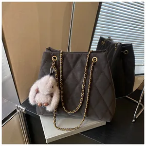 Detail van een grijze gewatteerde shopper met kettingriem en een pluche konijnenhanger