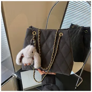 Detail van de donkergrijze gewatteerde tote bag met gouden ketting en pluche konijnenhanger