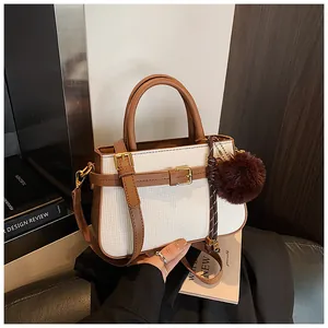 Detail of woven bucket bag with brown leather trim, gold hardware and plush charm