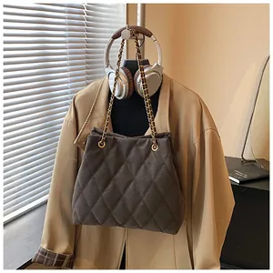 Detail van donkergrijze gewatteerde tas met gouden ketting aan een stijlvolle hanger