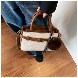 Close-up of contrast bucket bag in brown leather and white texture fabric with fur charm