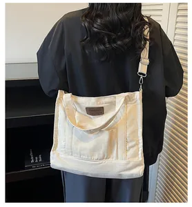 Detailed view of cream canvas tote bag with adjustable shoulder strap and brown leather tag