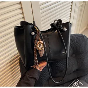 Detail of black tote bag featuring silver spherical hardware and branded round charm