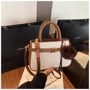 Detail view of contrast stitching and brown leather handle on retro white bucket bag