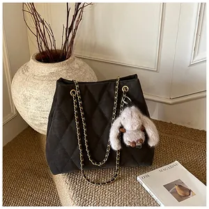 Detail van zwarte gewatteerde tote bag met gouden ketting en pluchen konijnenhanger