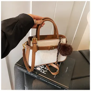 Close-up of retro bucket bag featuring brown leather trim and white woven texture detail
