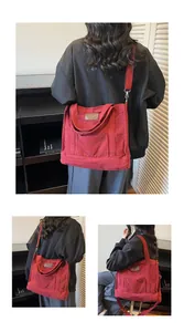 Detail of red canvas tote bag showing wide shoulder strap and front utility pocket