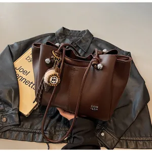 Detail view of dark brown leather tote bag featuring unique silver ball hardware and knot strap