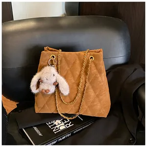 Detail van bruine gewatteerde shopper met gouden ketting en pluche konijnenhanger