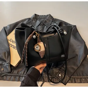 Detail of black leather tote bag with braided rope charm and ice cream pendant