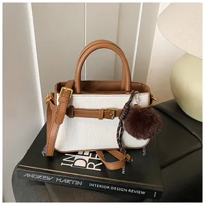 Close-up of white tweed bucket bag with brown leather trim and golden hardware