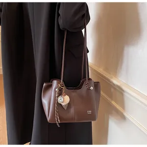 Detail of dark brown tote bag with white text print, ice cream pendant and slim dual straps