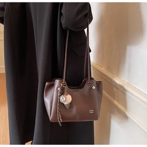 Detail of brown tote bag with smooth PU leather texture and unique ice cream charm