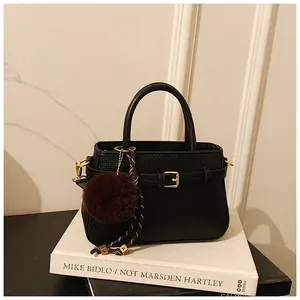 Detail of vintage black textured bucket bag with gold buckle and burgundy faux fur charm