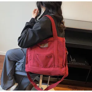 Dark red canvas tote bag with shoulder strap shown on model for daily commuting