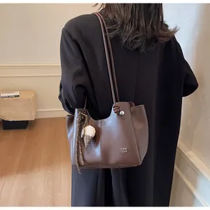 Detail of dark brown leather tote bag with knot strap and plaid ice cream charm