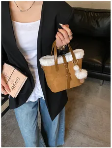 Detail of brown suede bucket bag with white faux fur trim and fluffy pom-pom charm