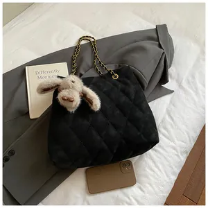 Detail van gewatteerde zwarte shopper met gouden ketting en pluche konijnenhanger